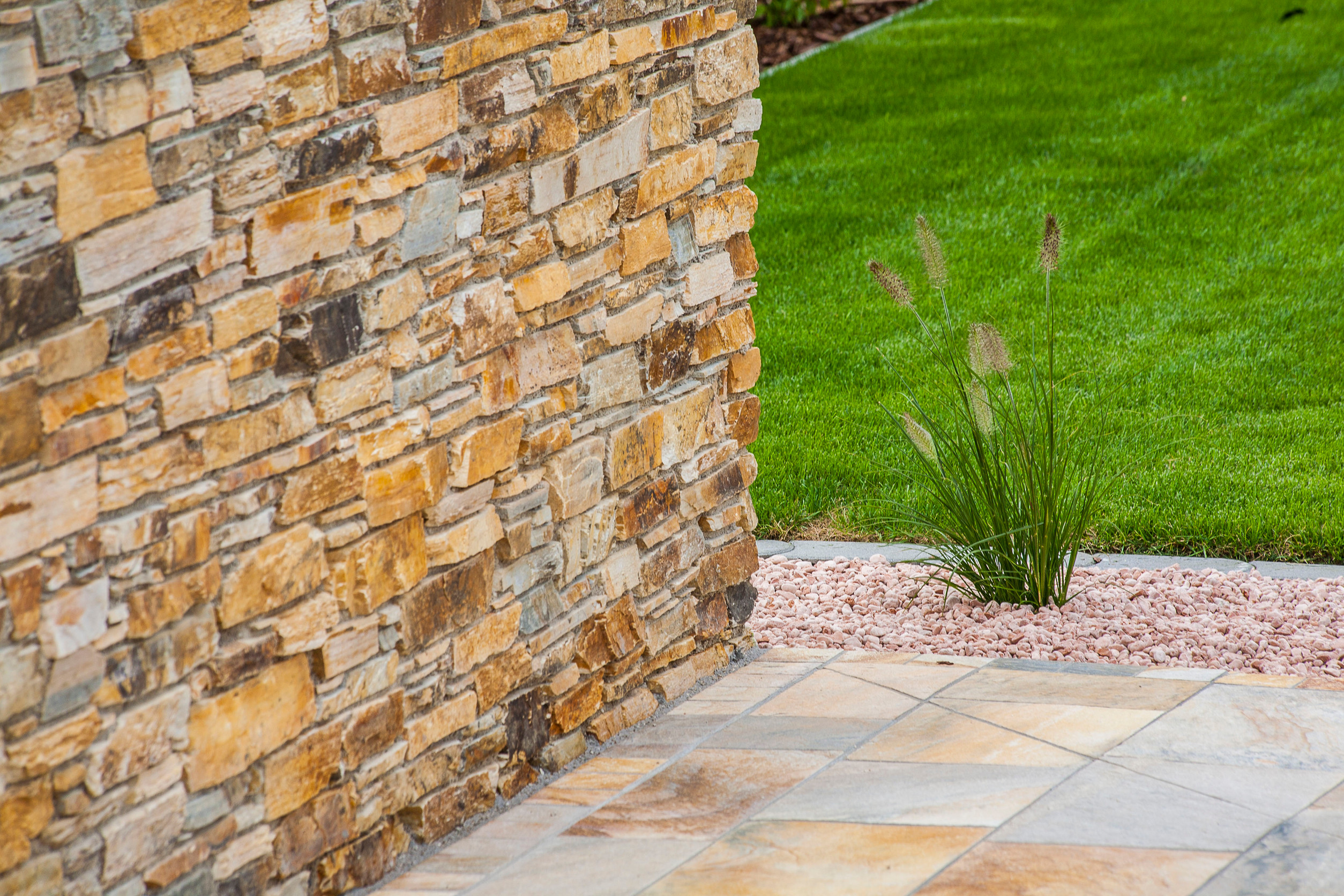 Rock wall in Oro Valley with freshly installed artificial turf, surrounded by desert landscaping.