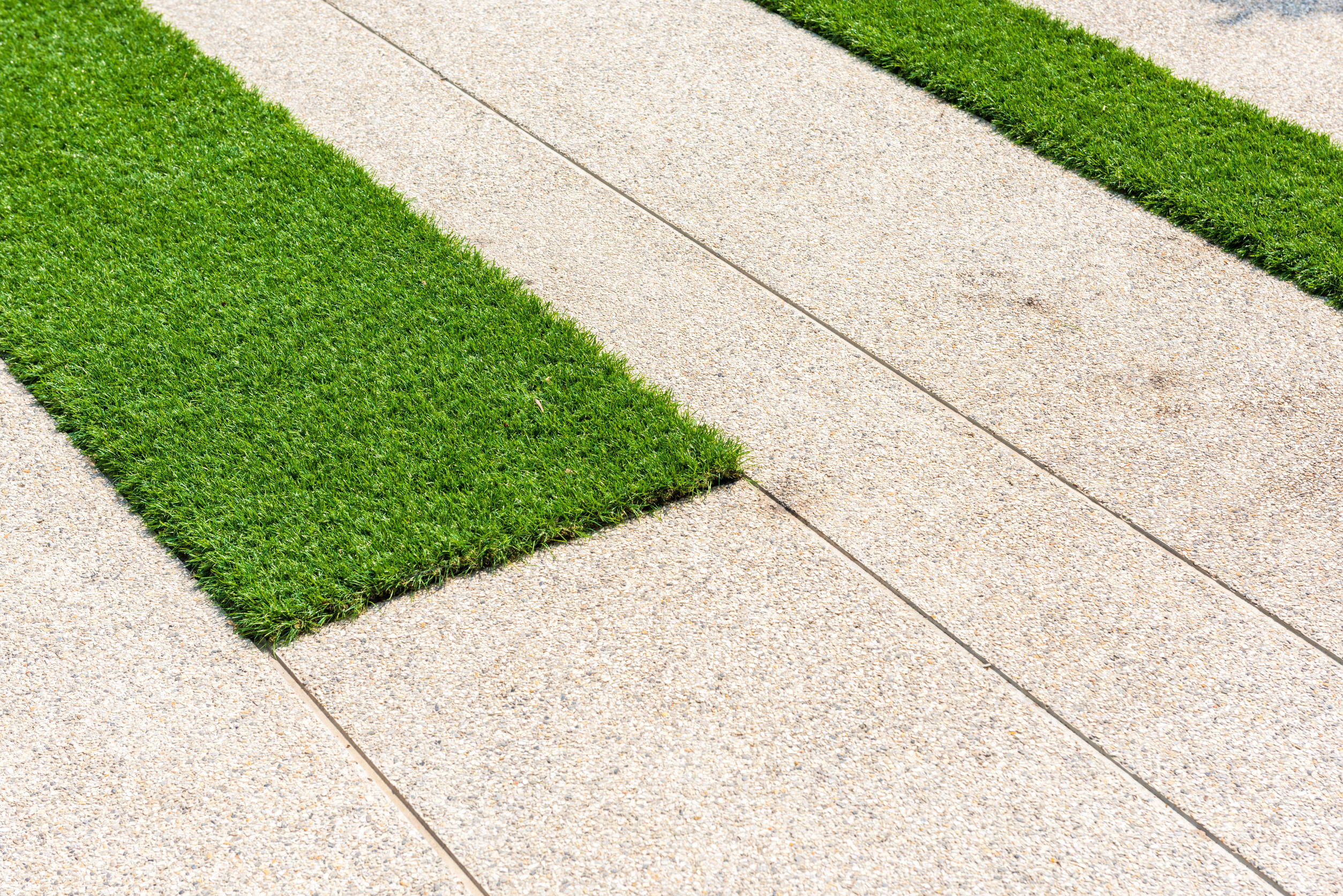Technician grooming artificial turf lawn in Tucson with power broom equipment